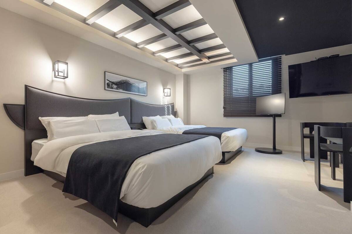 Een moderne hotelkamer met twee bedden, een bureau en een televisie.