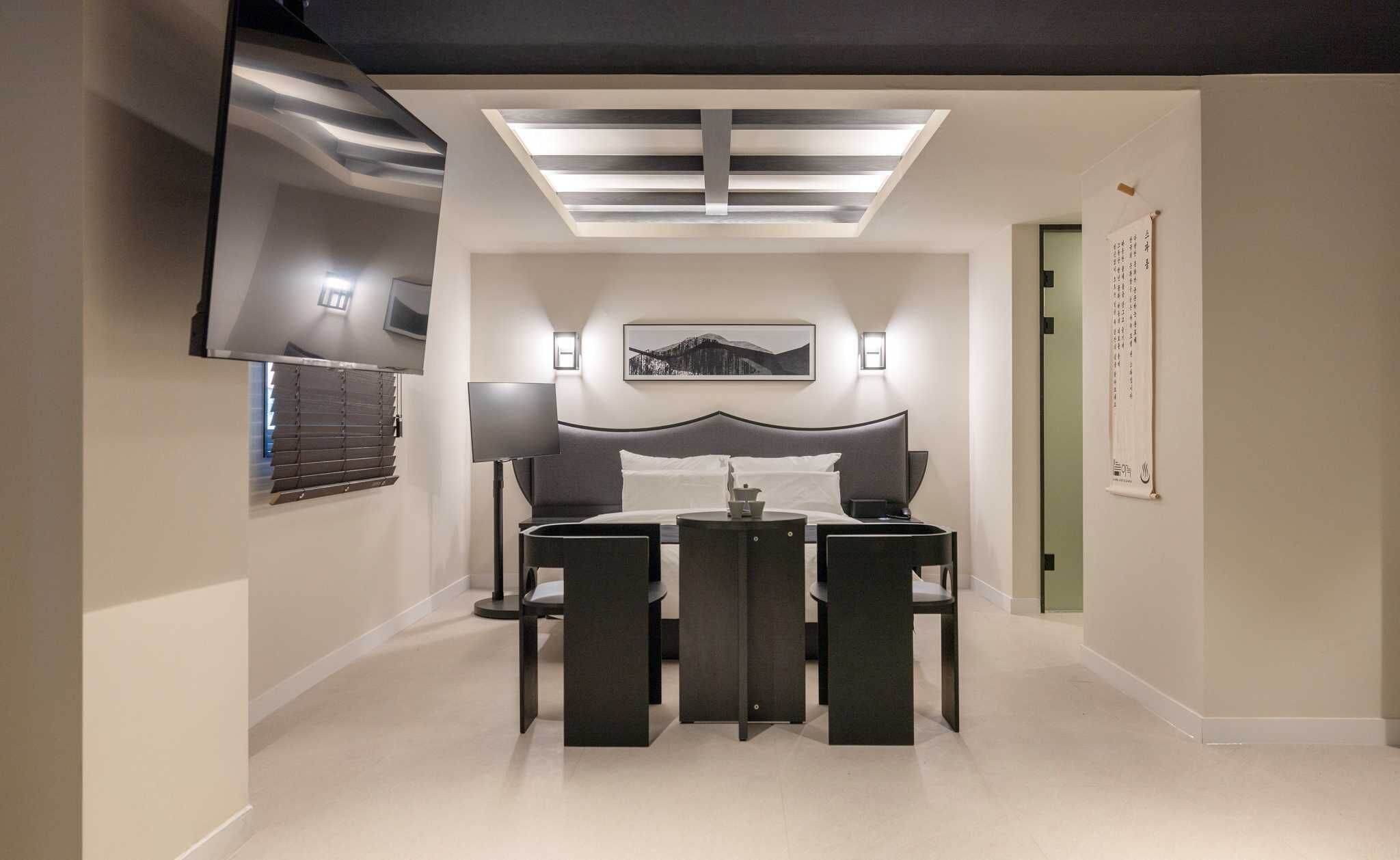 Un dormitorio moderno con cama, mesitas de noche, televisor y tragaluz.