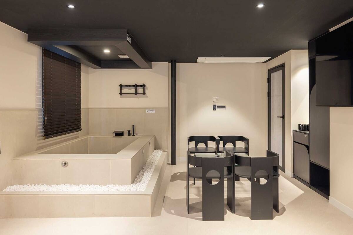 Een moderne badkamer met een groot bad, een klein tafeltje met stoelen en een koffiezetapparaat.