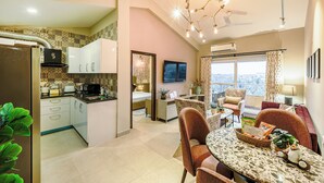 A modern kitchen with a dining area, a TV, and a balcony with a view. - Alaya Stays Veera Serina 3 BHK with Pool (Candolim)