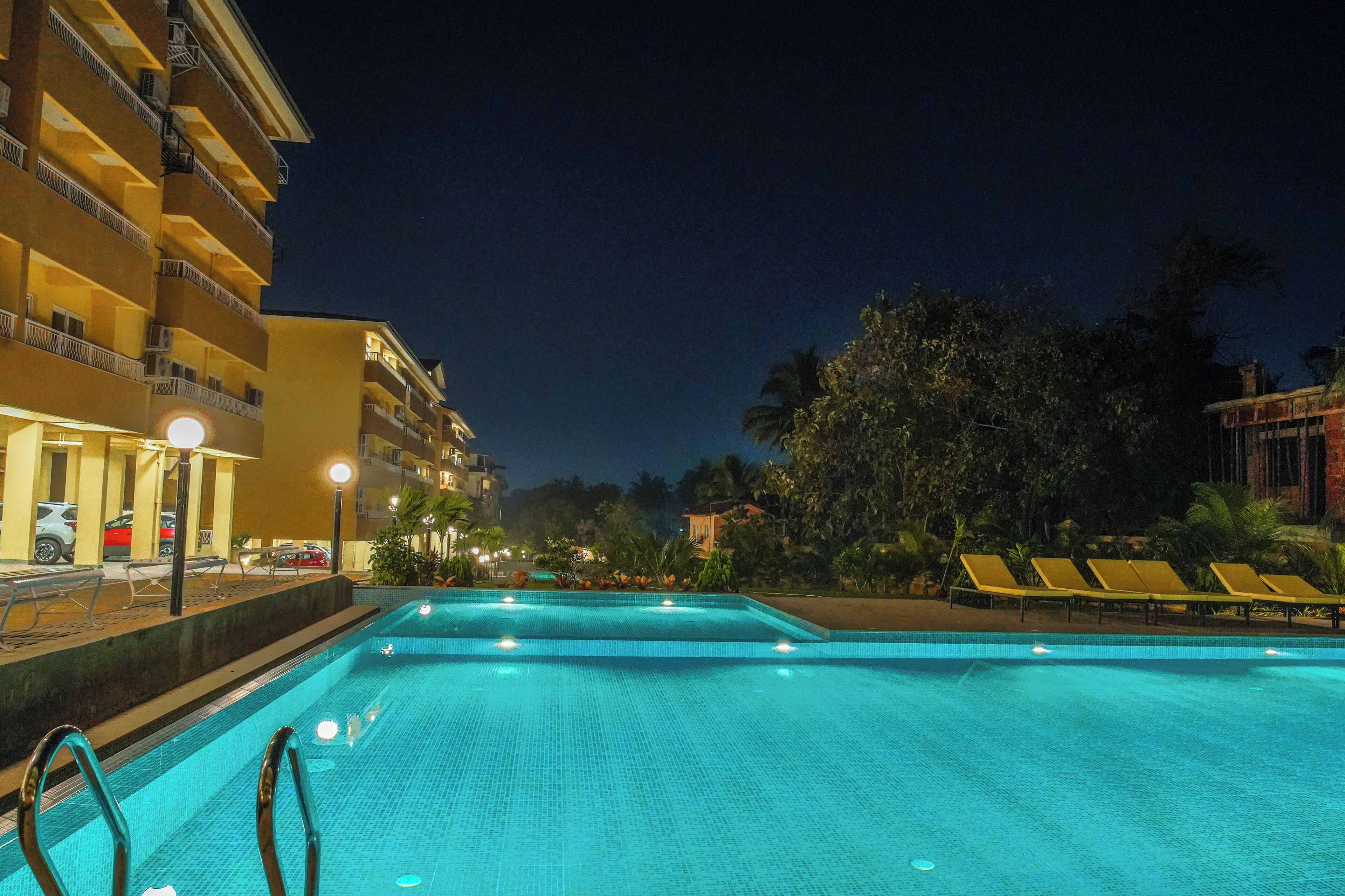 A swimming pool with lounge chairs and a building with balconies in the background.