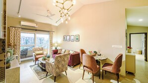 A modern living room with a sofa, chairs, a dining table, and a ceiling fan. - Alaya Stays Veera Serina 3 BHK with Pool (Candolim)