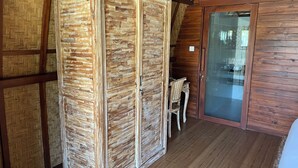 Een kamer met een houten garderobe, een houten tafel met een stoel en een glazen deur die naar buiten leidt.