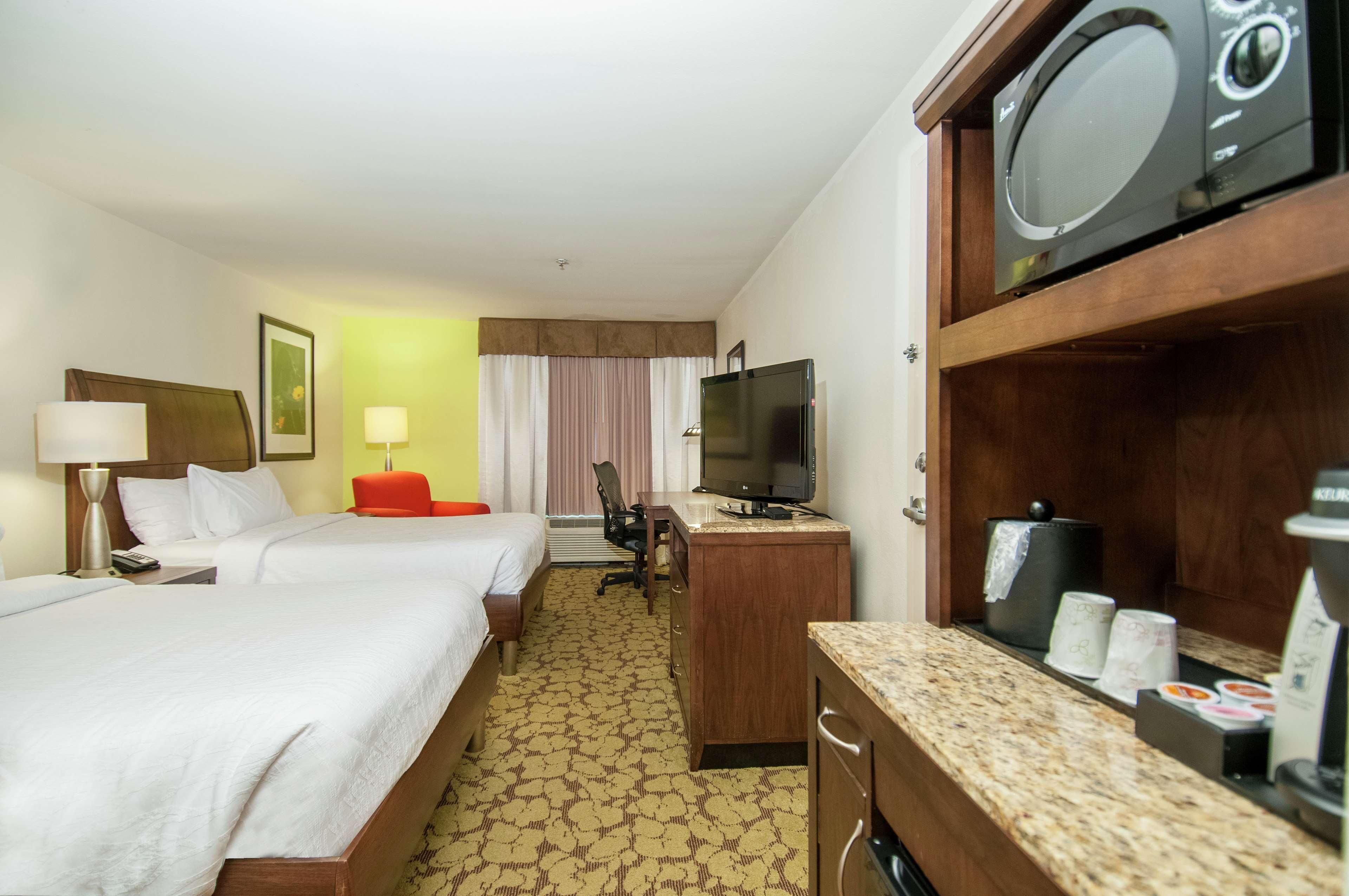 A hotel room with two beds, a desk, a television, and a microwave.