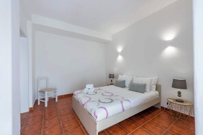 A bedroom with a bed, two bedside lamps, a chair, and a small table.