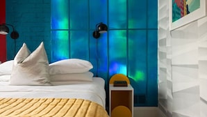 A modern bedroom with a bed, pillows, a bedside table, and a wall with a blue and green light effect. - 258 38th St. - Brownstone (Pittsburgh)