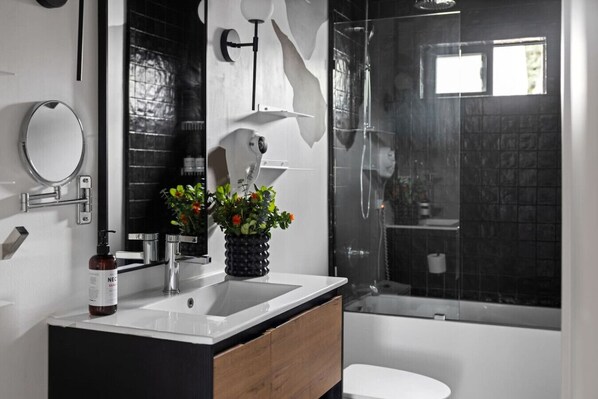Une salle de bain moderne avec un meuble-lavabo en bois, un grand miroir, un lavabo et un espace douche.