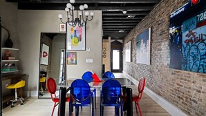 A modern office space with a brick wall, a glass table, and colorful chairs. - 258 38th St. - Brownstone (Pittsburgh)
