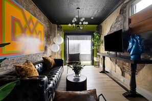 Un salon moderne avec un canapé en cuir noir, une table basse ronde et un grand tableau abstrait accroché au mur.