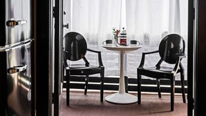 A room with a round table and two black chairs, a white coffee table, and a window with sheer curtains. - 258 38th St. - Brownstone (Pittsburgh)