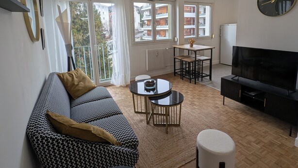 A modern living room with a sofa, TV, and dining area. - L'appart le 19, 2 bedrooms, near center, cathedral view (Clermont-Ferrand)