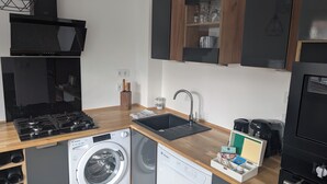 A compact kitchen with a built-in washer and dryer, a stove, and modern cabinetry. - L'appart le 19, 2 bedrooms, near center, cathedral view (Clermont-Ferrand)