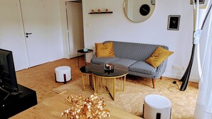 A living room with a sofa, coffee table, and decorative vase. - L'appart le 19, 2 bedrooms, near center, cathedral view (Clermont-Ferrand)