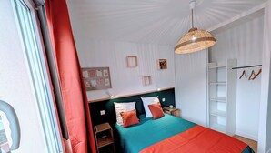 A bedroom with a bed, a bedside table, a hanging light fixture, a wardrobe, and a window with curtains. - L'appart le 19, 2 bedrooms, near center, cathedral view (Clermont-Ferrand)