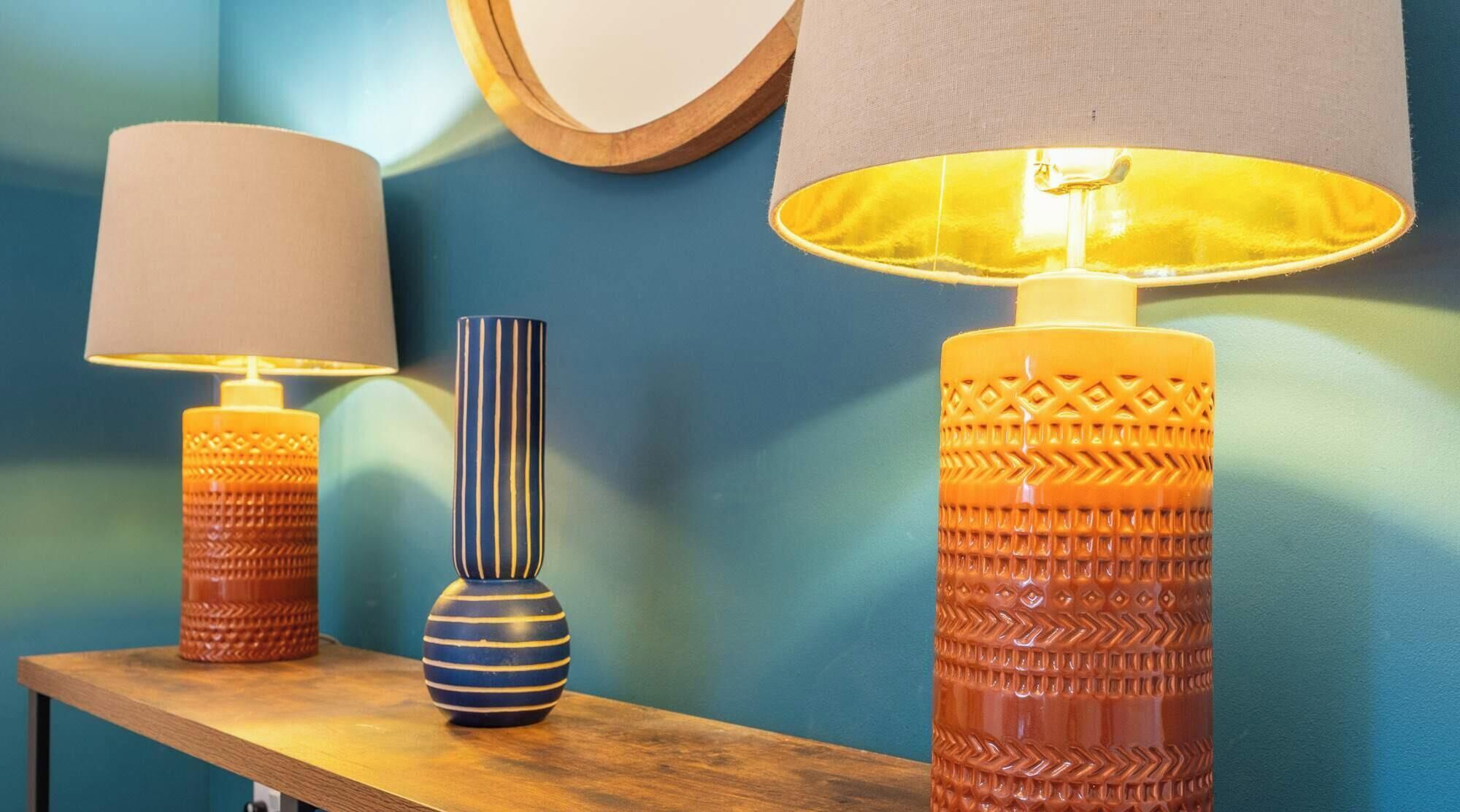 A table with three lamps and a vase.