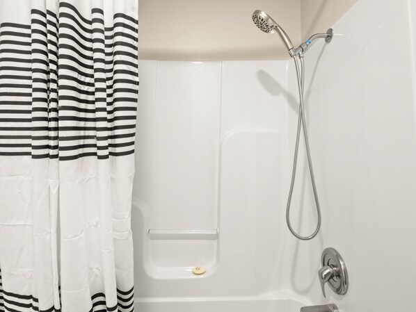Un baño con bañera, ducha y cortina a rayas.