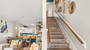 A staircase with wooden steps and a white handrail, leading to a landing with a decorative wall. - Big Fam Lodge Townhomes - Near Casinos & Golf - Sleeps 24 (Lake Charles)