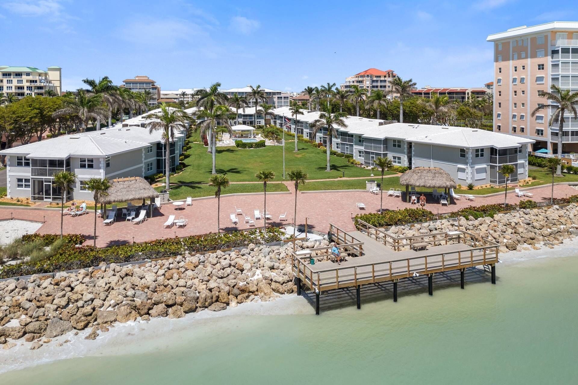 A resort with multiple buildings, a central lawn area, and a dock extending into the water.