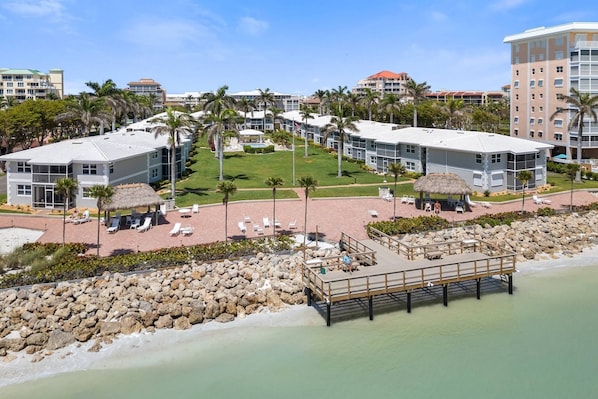 A resort with multiple buildings, a central lawn area, and a dock extending into the water.