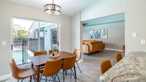 A modern kitchen with a marble countertop, a dining area with orange chairs, and a large window overlooking a pool. - Private Coastal Getaway to Connect and Celebrate (Palm Harbor)