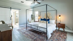 A bedroom with a four-poster bed, a ceiling fan, a patterned rug, and bedside lamps. - Private Coastal Getaway to Connect and Celebrate (Palm Harbor)