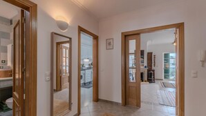 A hallway with wooden doors leading to a kitchen and a living area.