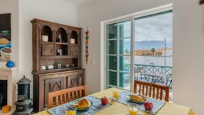 A dining area with a table set for breakfast, a wooden cabinet, and a view of the city through a large window.