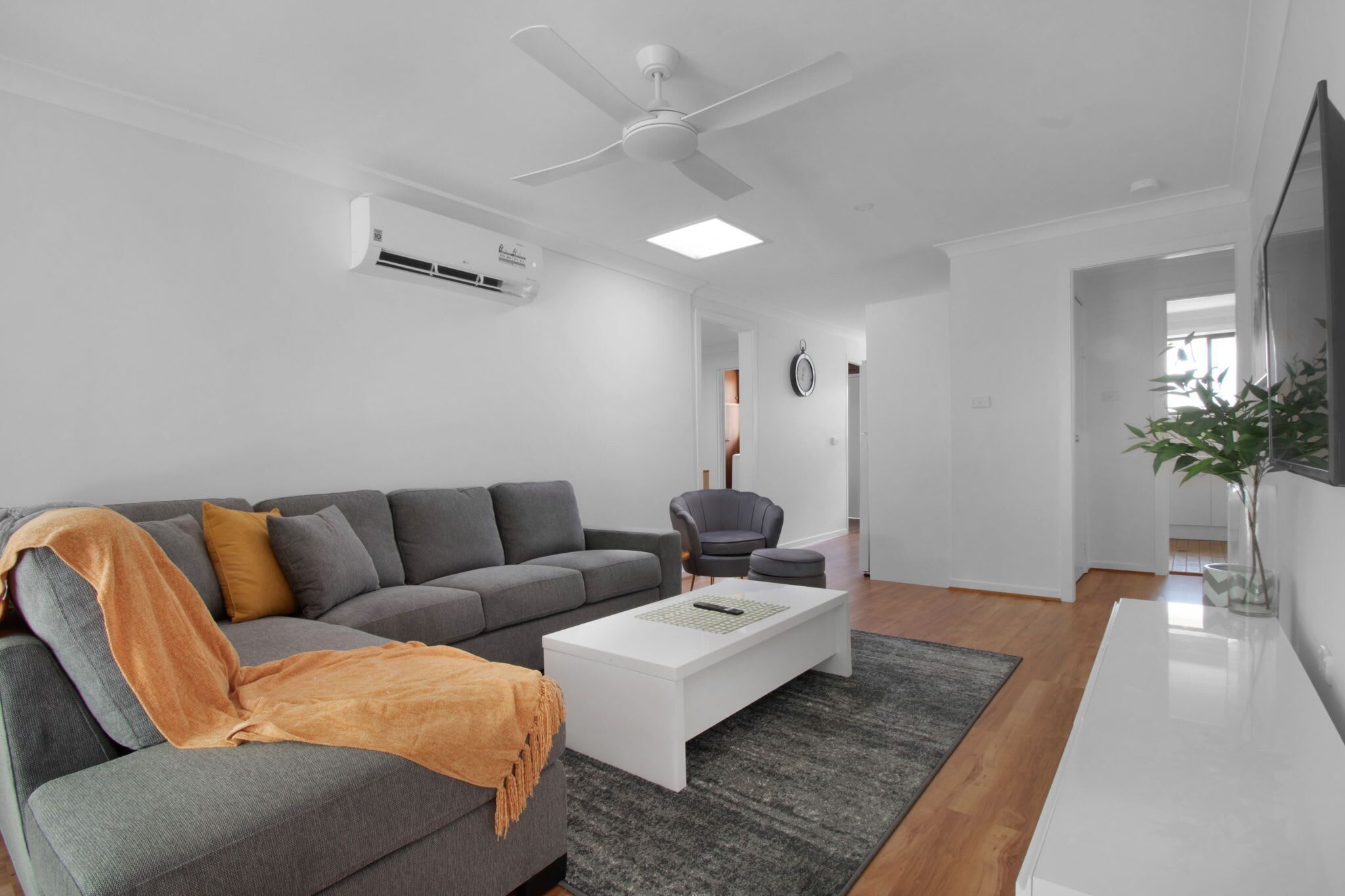 A modern living room with a grey sofa, a white coffee table, and a ceiling fan.