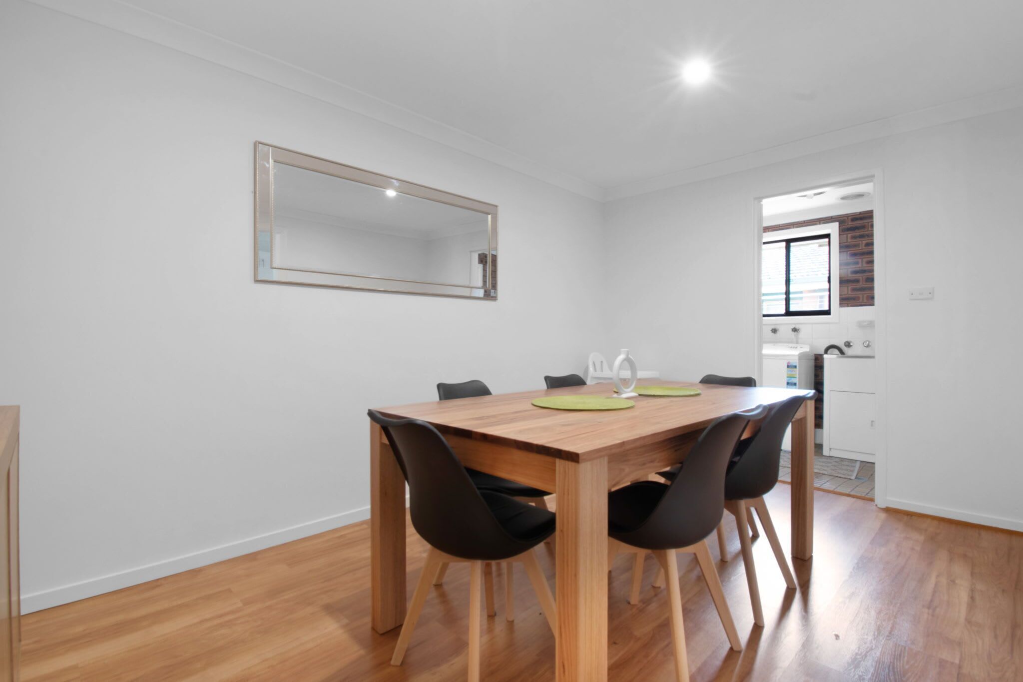 A dining area with a wooden table, black chairs, and a mirror on the wall.
