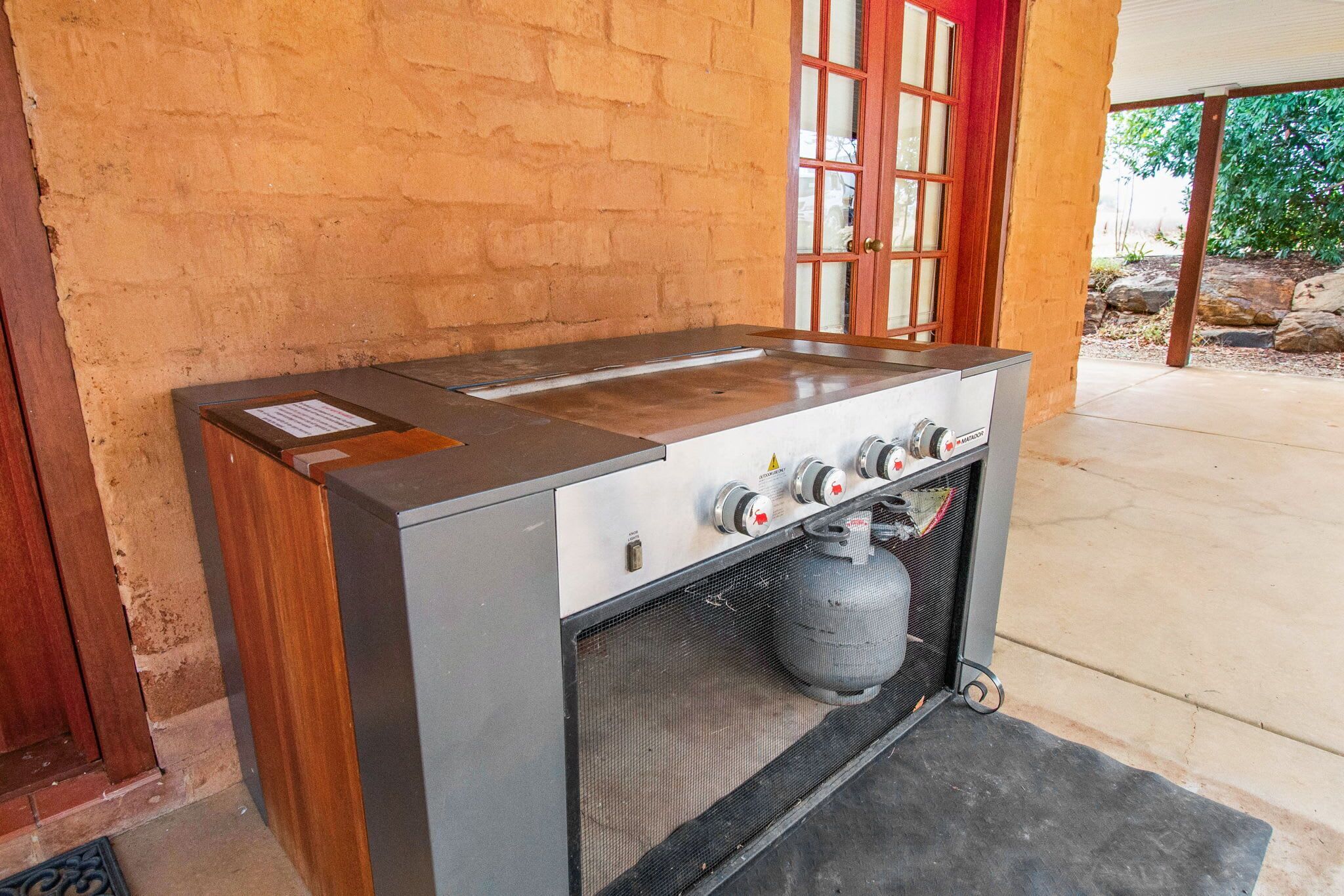 A gas stove with four burners and a gas cylinder.