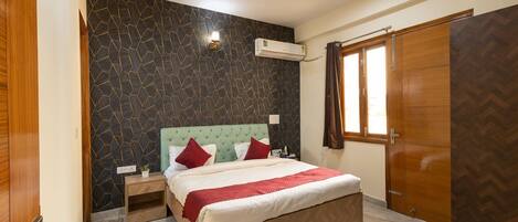 A bedroom with a bed, nightstands, a ceiling fan, an air conditioning unit, and a wardrobe.