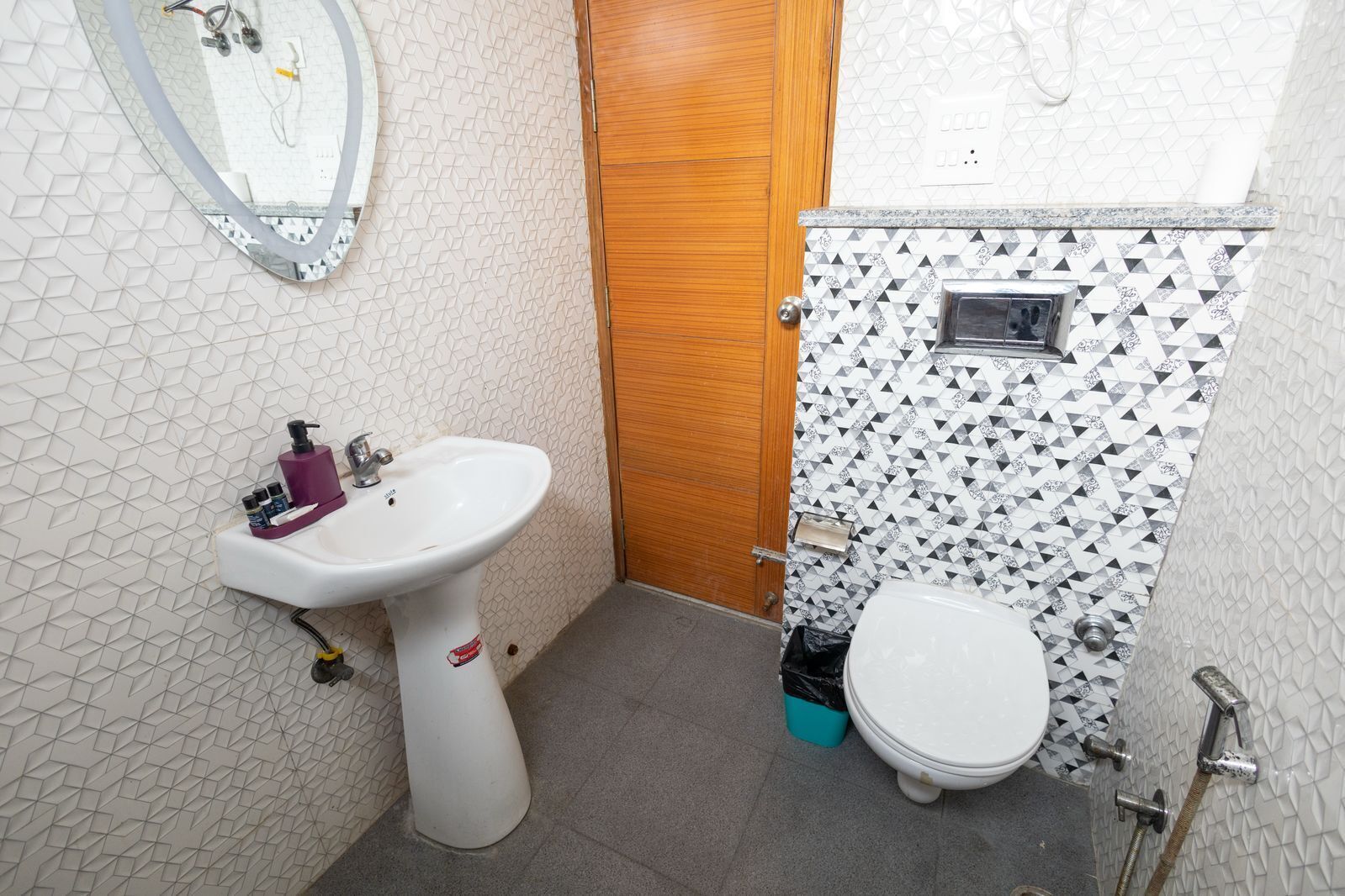 Un baño pequeño con un lavabo pedestal blanco, un inodoro y una zona de ducha.