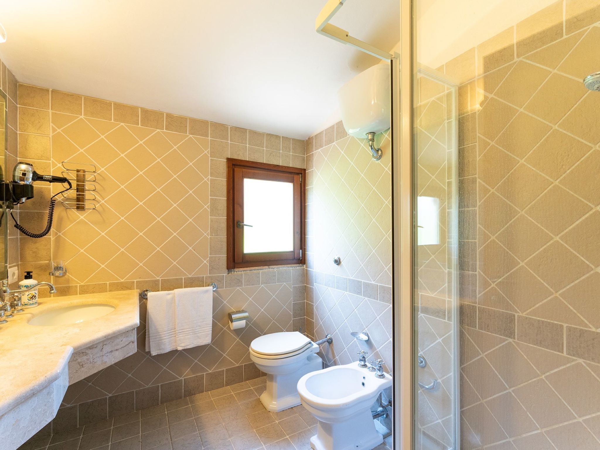 Un bagno con lavandino, WC, bidet e cabina doccia in vetro.