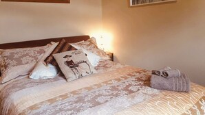 A neatly made bed with floral-patterned bedding, a decorative pillow, and a rolled towel on the side. - Anglesea House Inn (Blenheim)