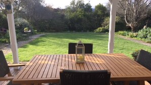 A wooden deck with a table and chairs, overlooking a well-maintained lawn and garden. - Anglesea House Inn (Blenheim)