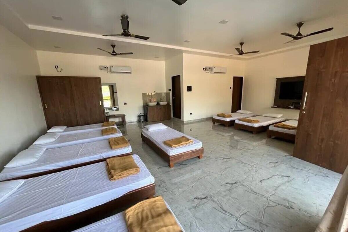 A hotel room with multiple beds, a TV, ceiling fans, and a bathroom with a mirror and sink.