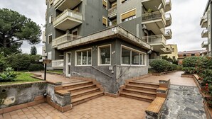 Um edifício residencial de vários andares com varandas, um pátio central com degraus e uma área ajardinada.