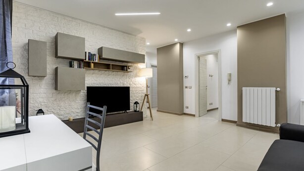 Uma sala de estar moderna com televisão de tela plana, estantes embutidas, lareira e área de jantar com mesa e cadeiras.