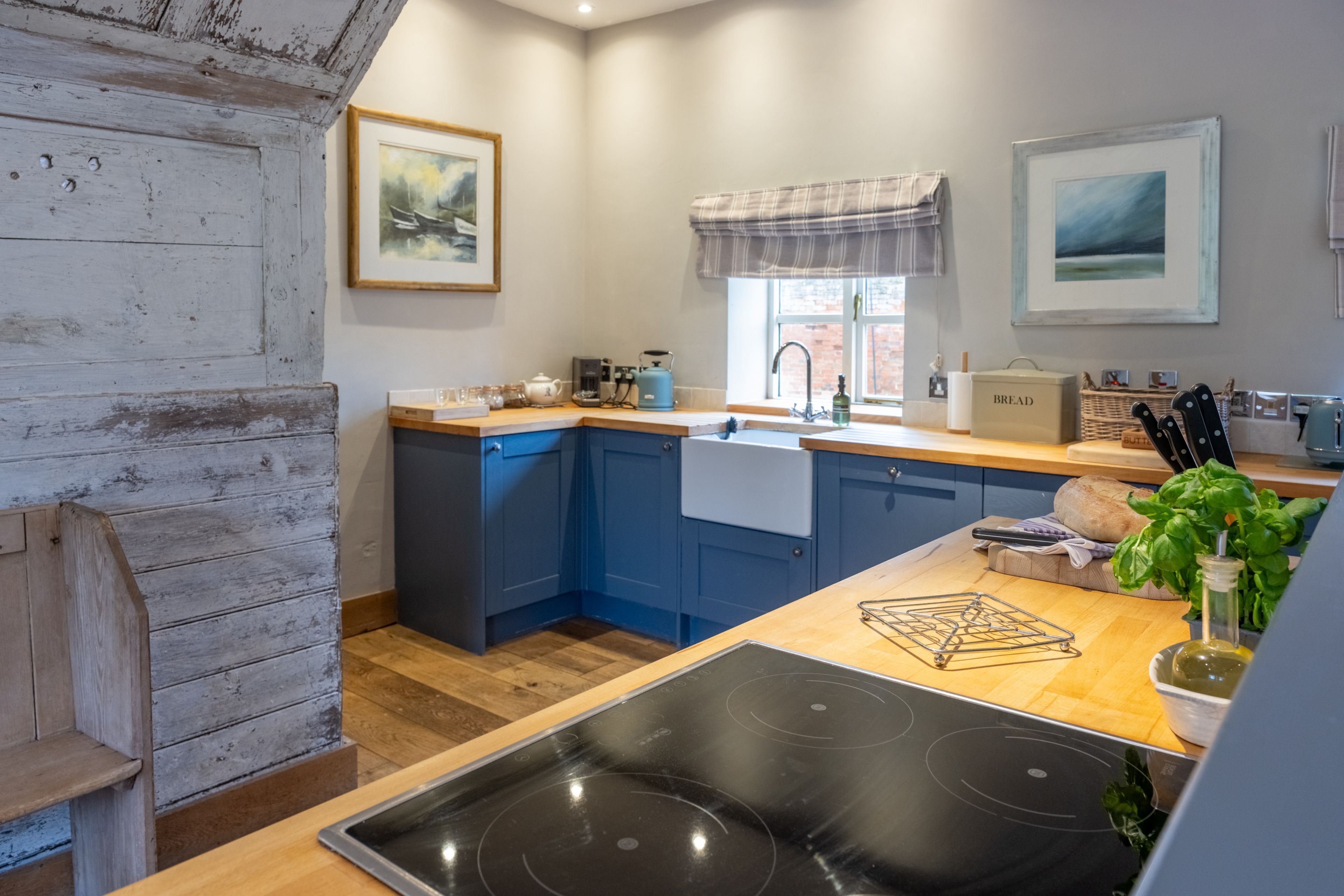 Una cocina moderna con armarios azules, encimera de madera, estufa negra y ventana con vistas.