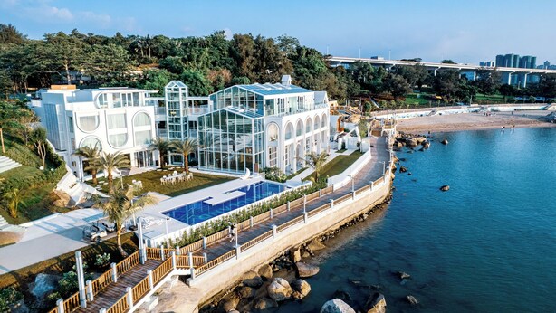 A modern resort with a large glass building, a swimming pool, and a beach view. - Masuland (Shantou)
