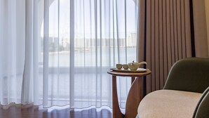 A room with a view of a body of water, a table with a teapot and cups, and a chair. - Masuland (Shantou)