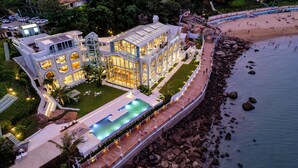 A luxurious resort with a large pool, a beach, and a rocky shoreline. - Masuland (Shantou)
