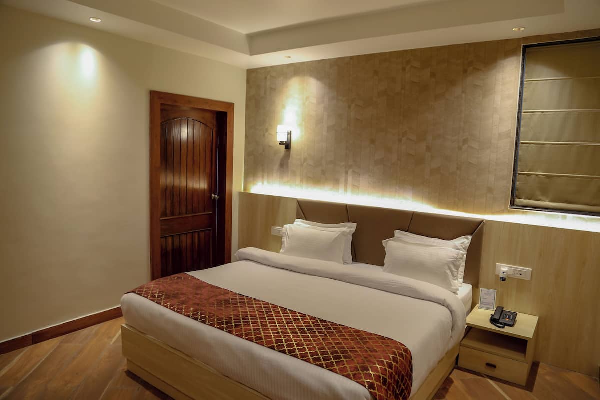 A hotel room with a large bed, a nightstand with a phone, and a wooden door.