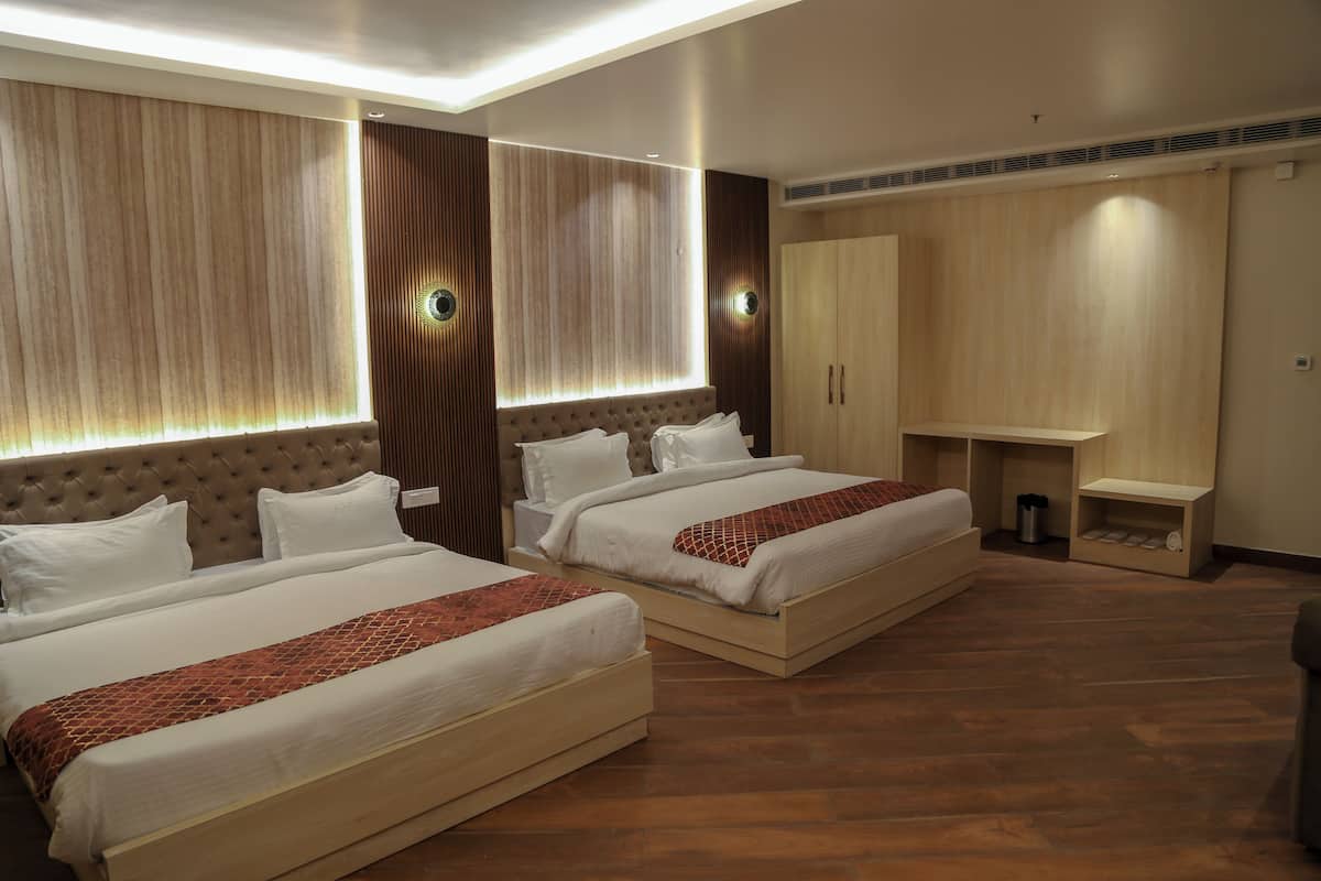 A hotel room with two beds, a wardrobe, and a small desk.