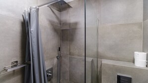 Une douche moderne avec une porte en verre, des carreaux gris et un porte-serviettes.