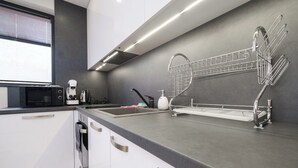 Een moderne keuken met een ingebouwde magnetron, koffiezetapparaat en een roestvrijstalen spoelbak met afdruiprek.