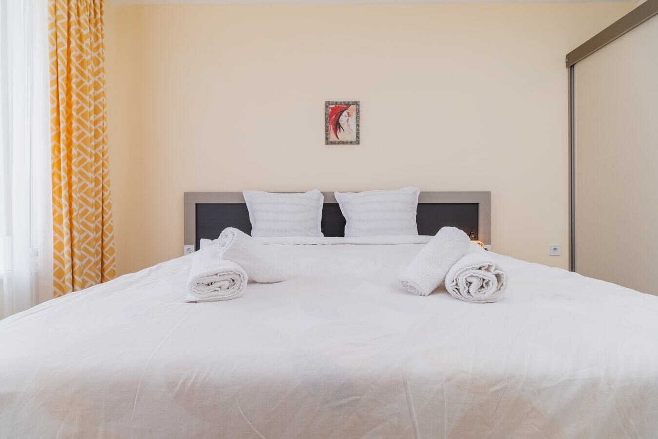 Una cama bien hecha con sábanas blancas y dos toallas enrolladas sobre la cama.