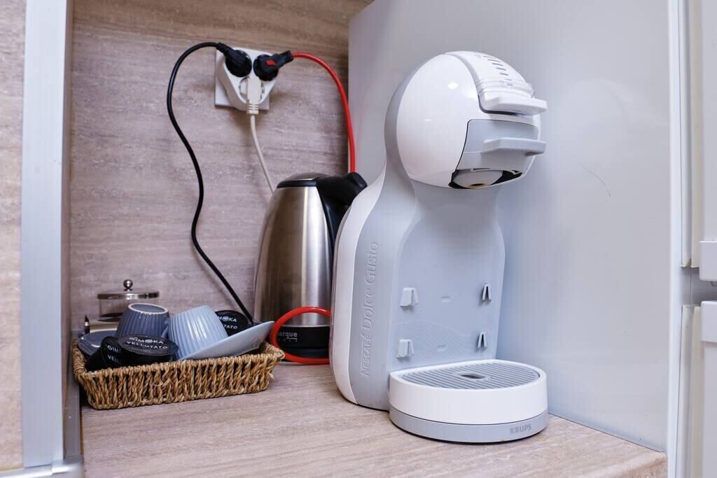 Eine Kaffeemaschine, ein Wasserkocher und ein Tablett mit Tassen auf einer Holzauslage.