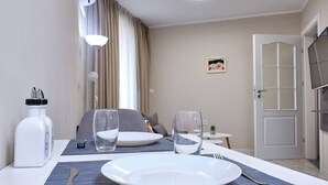 A neatly arranged dining area with a table set for two, including plates, glasses, cutlery, and a water bottle. - Cozy 1-bed Apartment 2 (Plovdiv)