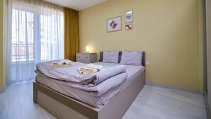 A bedroom with a bed, a nightstand, and a window with curtains. - Cozy 1-bed Apartment 2 (Plovdiv)